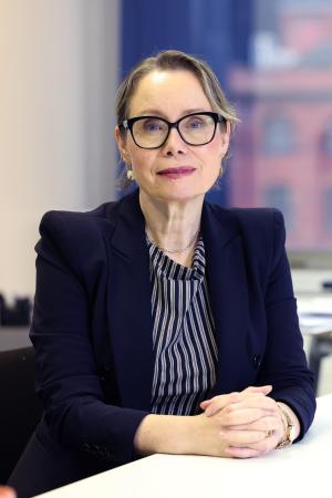 The Commissioner for Survivors of Institutional Childhood Abuse, Fiona Ryan, sitting at a desk with her hands folded looking at the camera